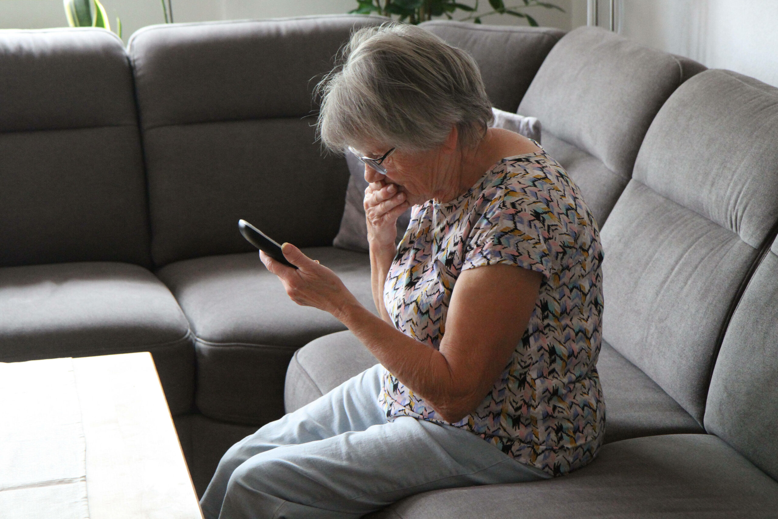 Eine ältere Frau hält ihr Telefon schockiert in der Hand. (Symbolbild)