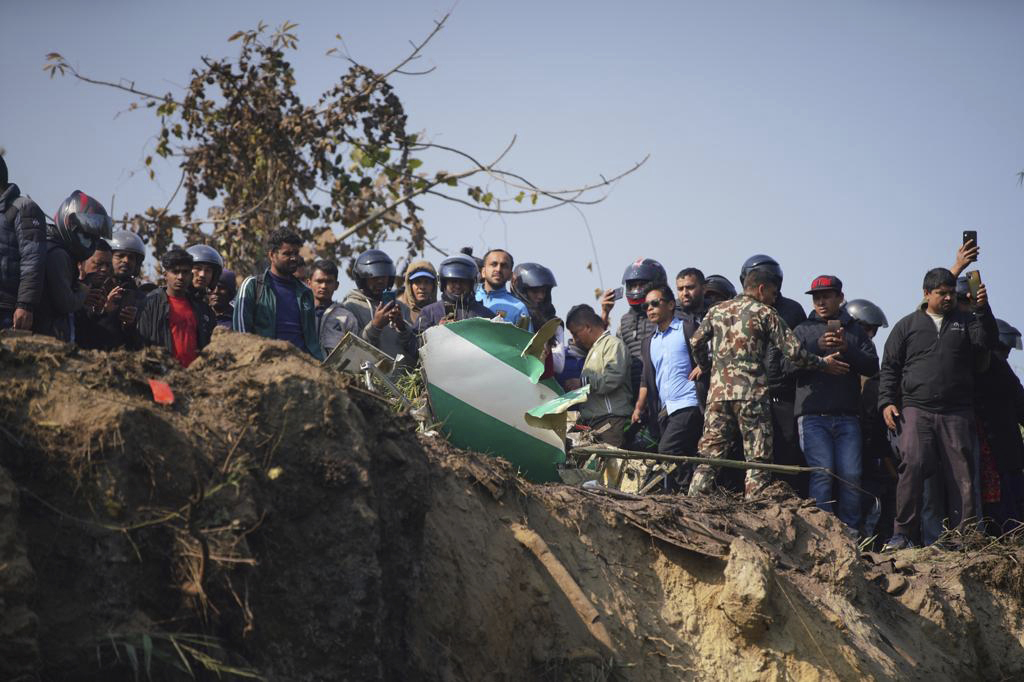 Einheimische schauen auf das Wrack eines abgestürzten Passagierflugzeugs und die Rettungskräfte bei den Bergungsarbeiten.